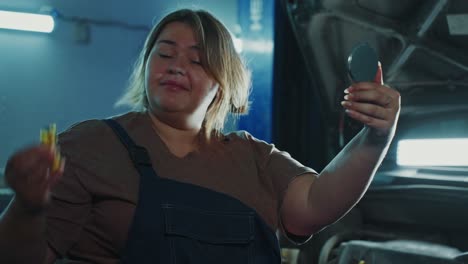 woman mechanic checking her hair in a garage