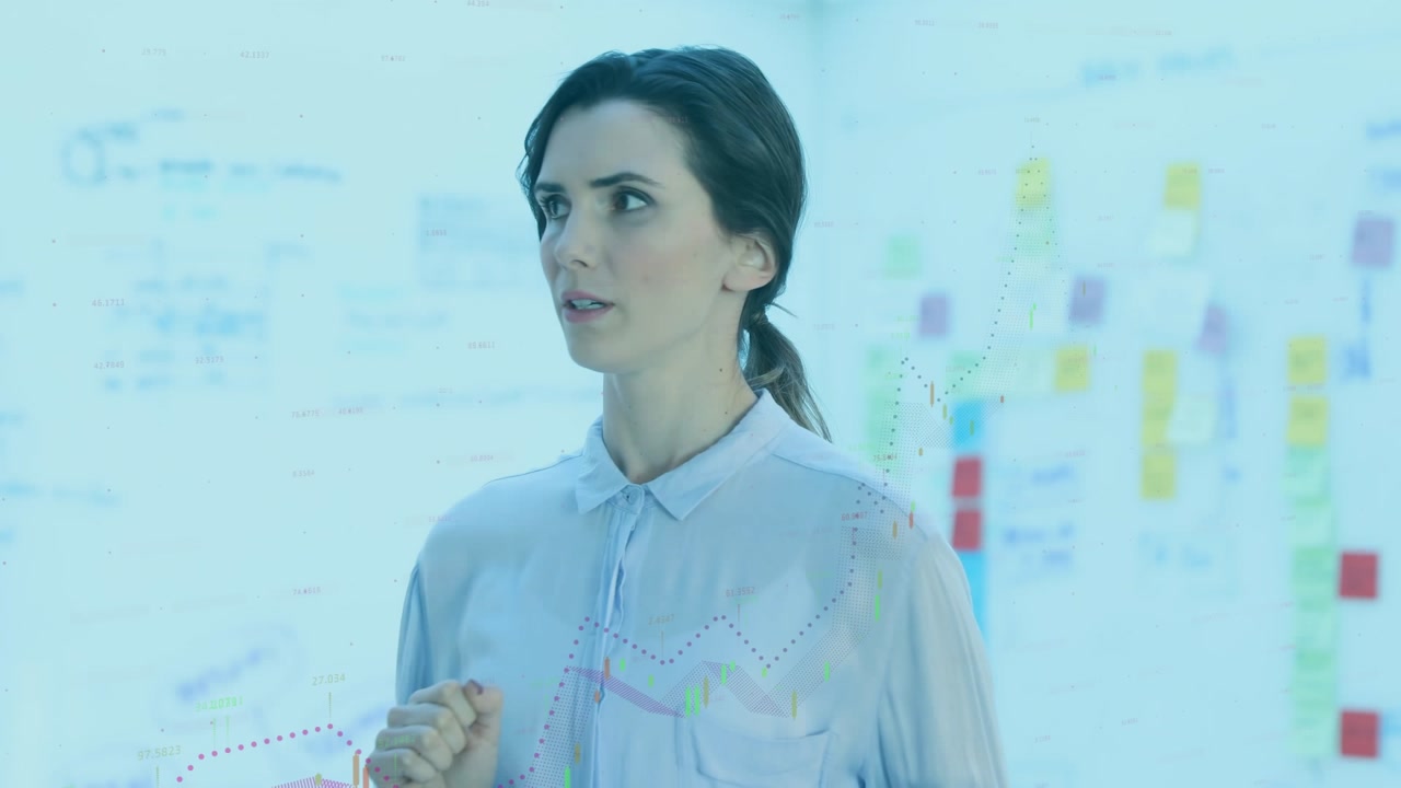 Animation of financial graphs and data over happy caucasian woman using tablet