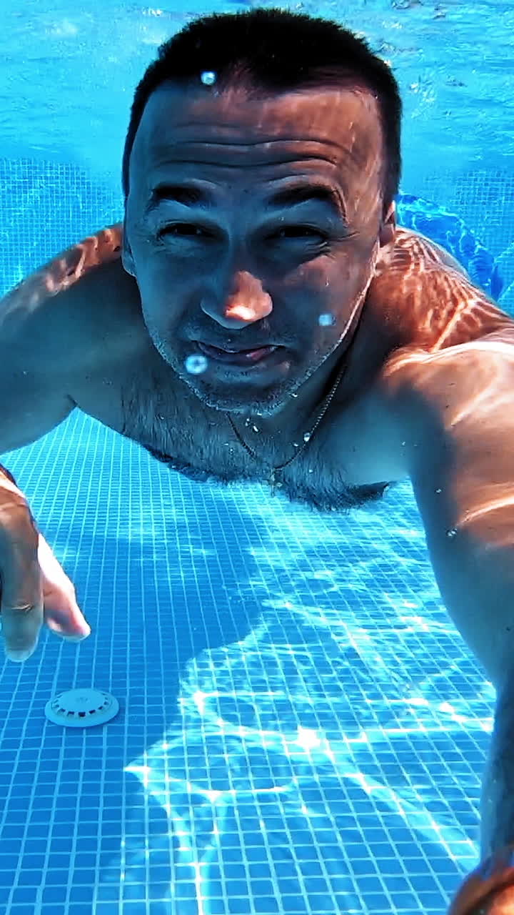 Swimming underwater man in pool. Man doing underwater selfie shot in pool