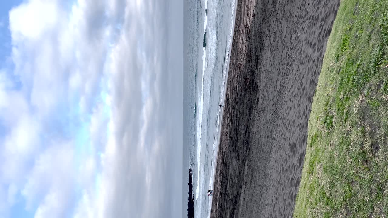 포르투갈의 모래 해안을 따라 걸어가는 사람들의 실루과 바다와 하늘의 풍경적인 배경은 평화로운 분위기를 만니다.