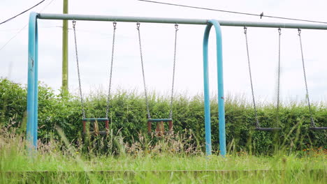 Verlassener-Kinderspielplatz-Mit-Leeren,-Verlassenen-Schaukeln-Und-überwuchertem-Gras-Während-Der-Coronavirus-Pandemie