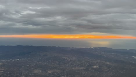 Orange-horizon-during-the-sunrise-shot-from-an-airplane-cabin-in-a-real-flight-near-Almeria,-Mediterranean-coast