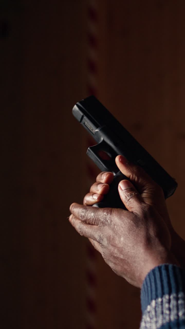 Vertical video Man reloading handgun in indoor shooting range, close up