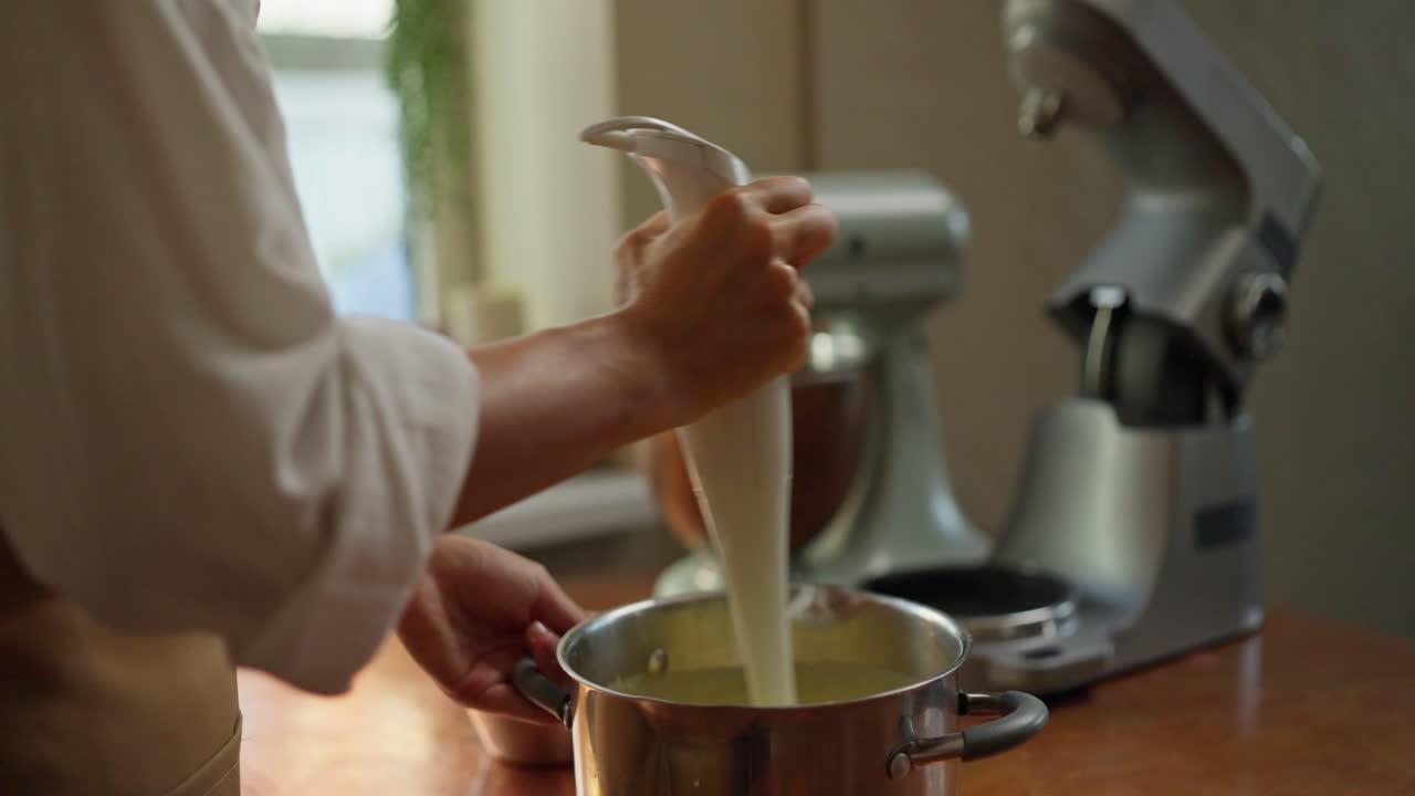 Un cuoco usa uno sbattitore elettrico per mescolare gli ingredienti in una ciotola