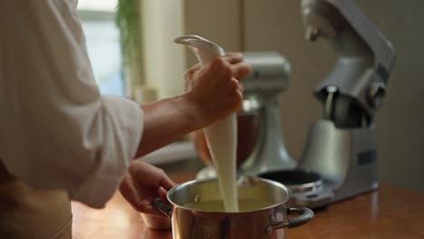 un chef usa un mezclador de mano para mezclar ingredientes en un cuenco.