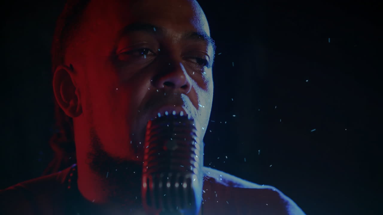 Male singer performing on music stage, with retro microphone, red blue lights, floating drops