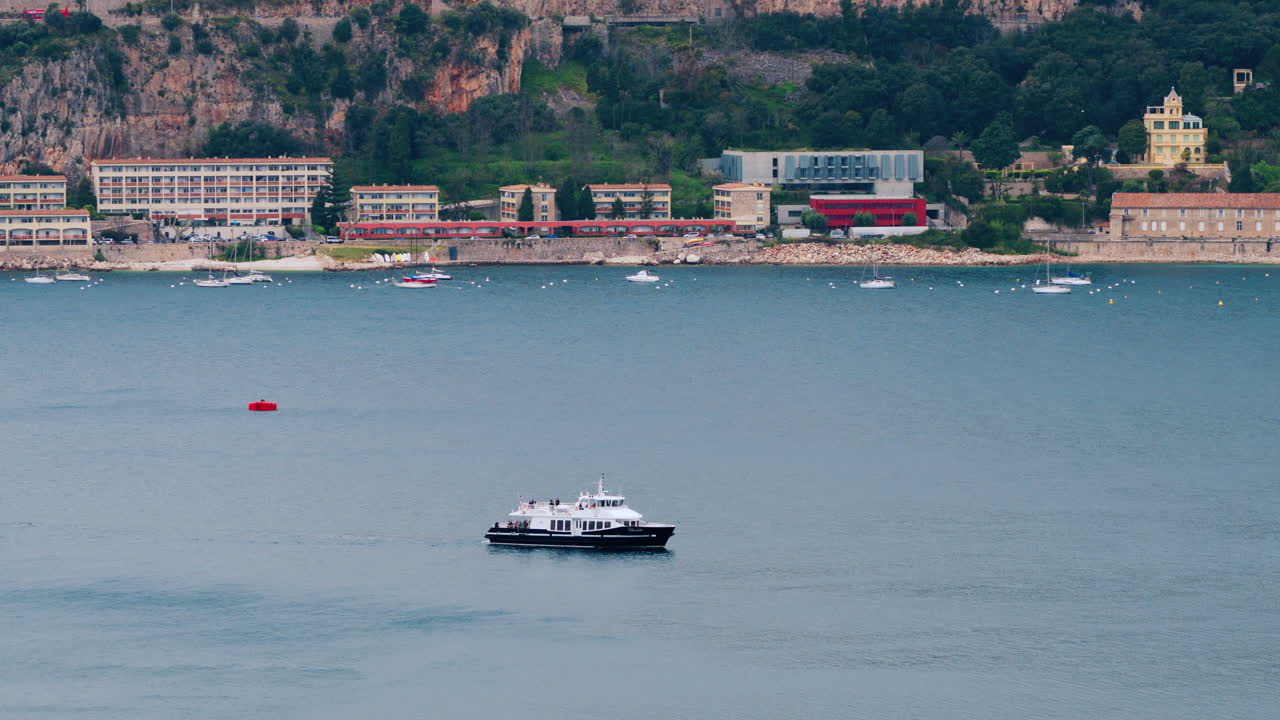 Villefranche-sur-Mer, France - April 18, 2025: Distant view of a boat moving on the sea with buildings on the background