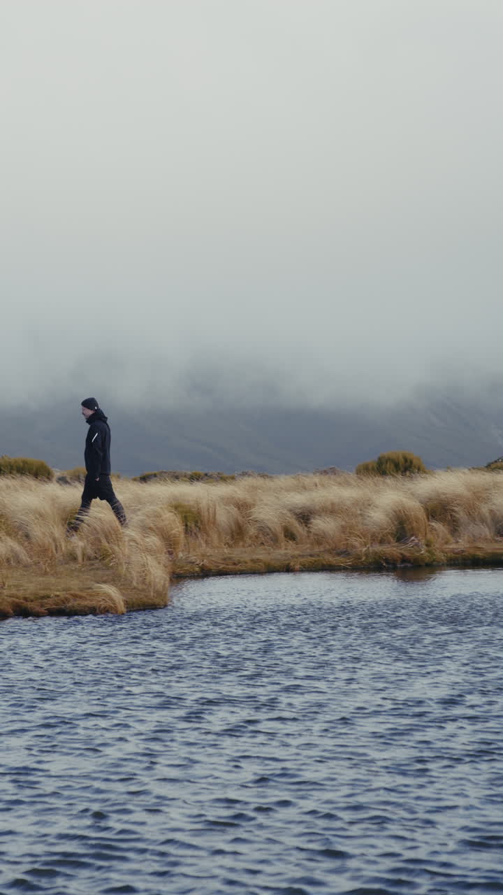 Person Hiking in Misty Mountains by a Lake