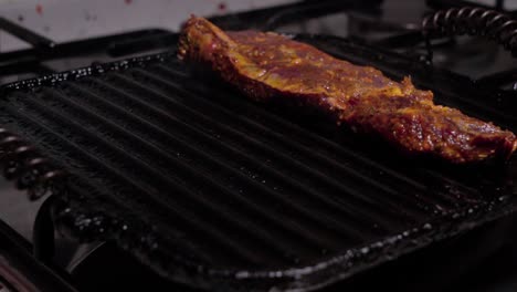 hands put two marinated beef steaks on old fashioned cast iron griddle grill