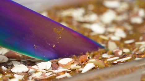 large sharp knife slicing delicious desert with almond nut shavings in a glass baking dish