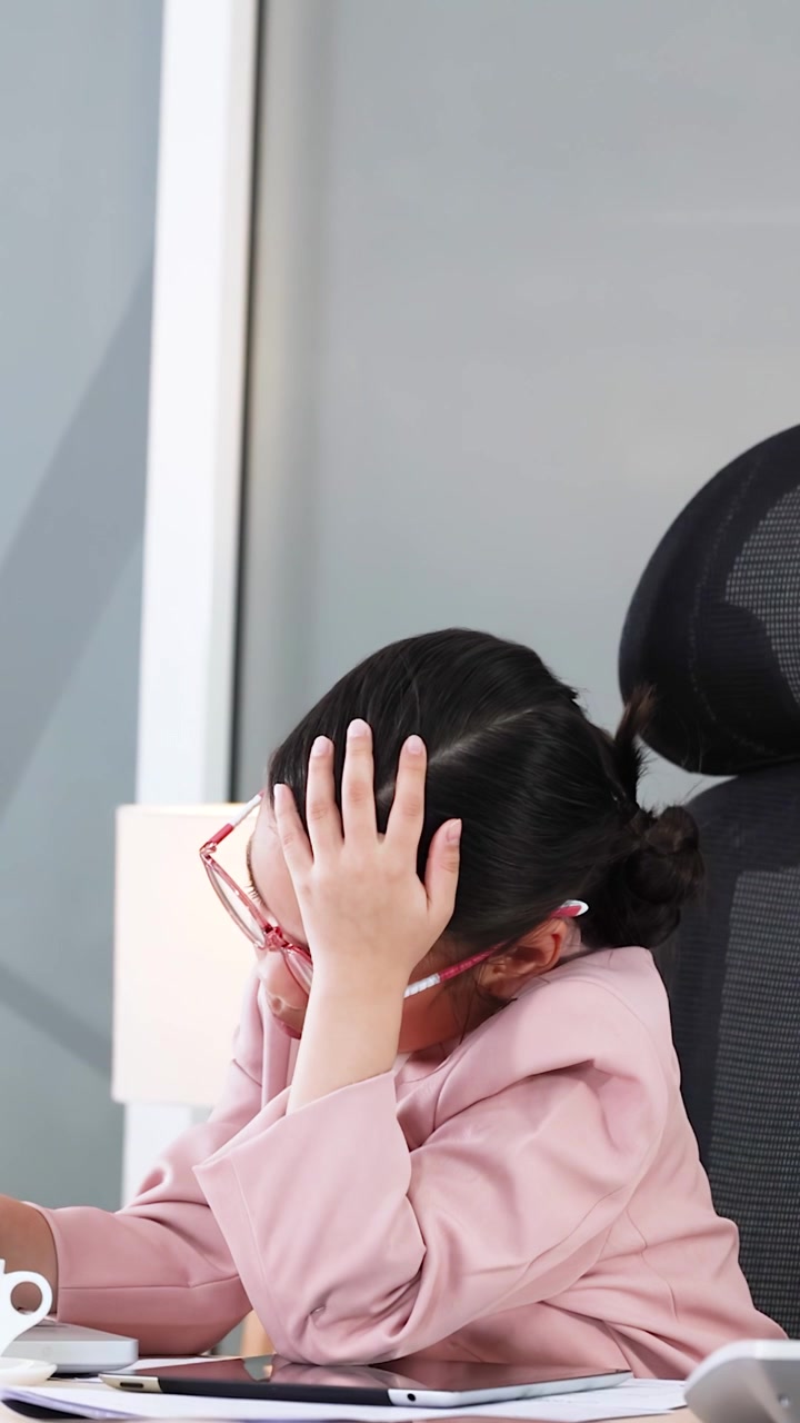 Una giovane ragazza vestita da donna d'affari professionista esprime frustrazione e stress alla sua scrivania