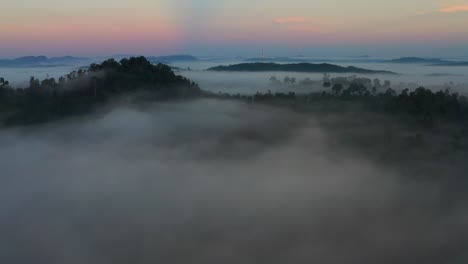 a wonderful sunrise aerial cinematic shot above cloud an mountains in the malaysian rain forest, slow down through the mist