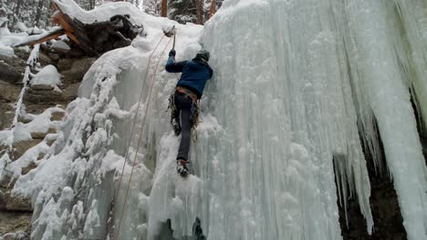 ice climber climbing frozen cliff during winter 4k