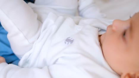 sonriente madre joven sosteniendo al bebé en el regazo mientras juega en la cama en el dormitorio 4k