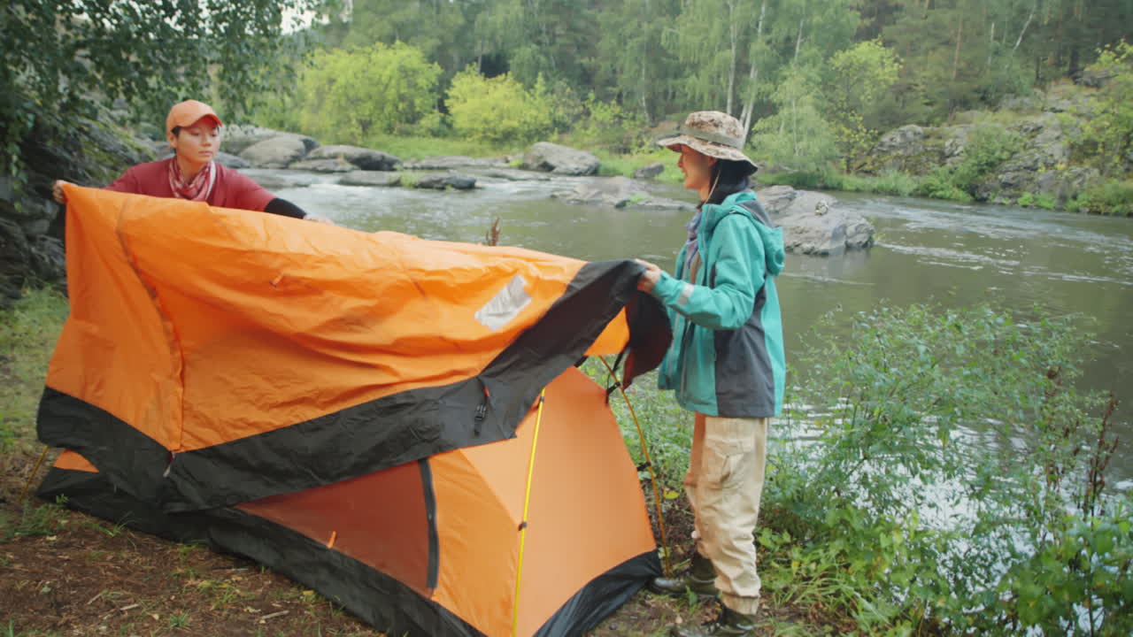 Female Tourists Covering Tent with Tarp