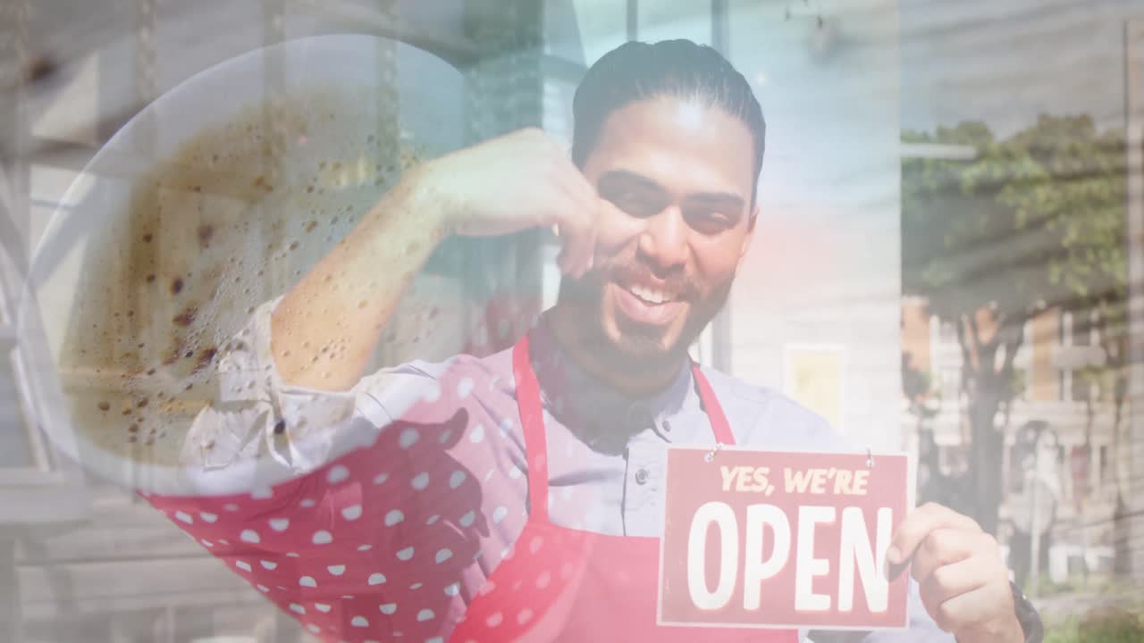 Close up of a coffee cup against african american male waiter holding open sign outside the cafe