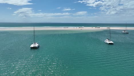 Volando-Sobre-El-Agua-Entre-Catamaranes-Hacia-Vehículos-Estacionados-En-Un-Banco-De-Arena