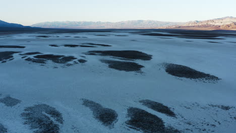 drone volando bajo sobre un valle de terreno accidentado y duro cubierto de salinas en el campo de golf devils en el parque nacional del valle de la muerte, california