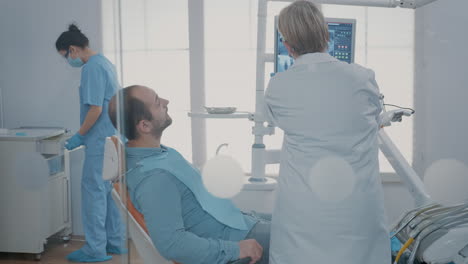 médico apuntando al diagnóstico de exploración de rayos x en el monitor en el gabinete de odontología