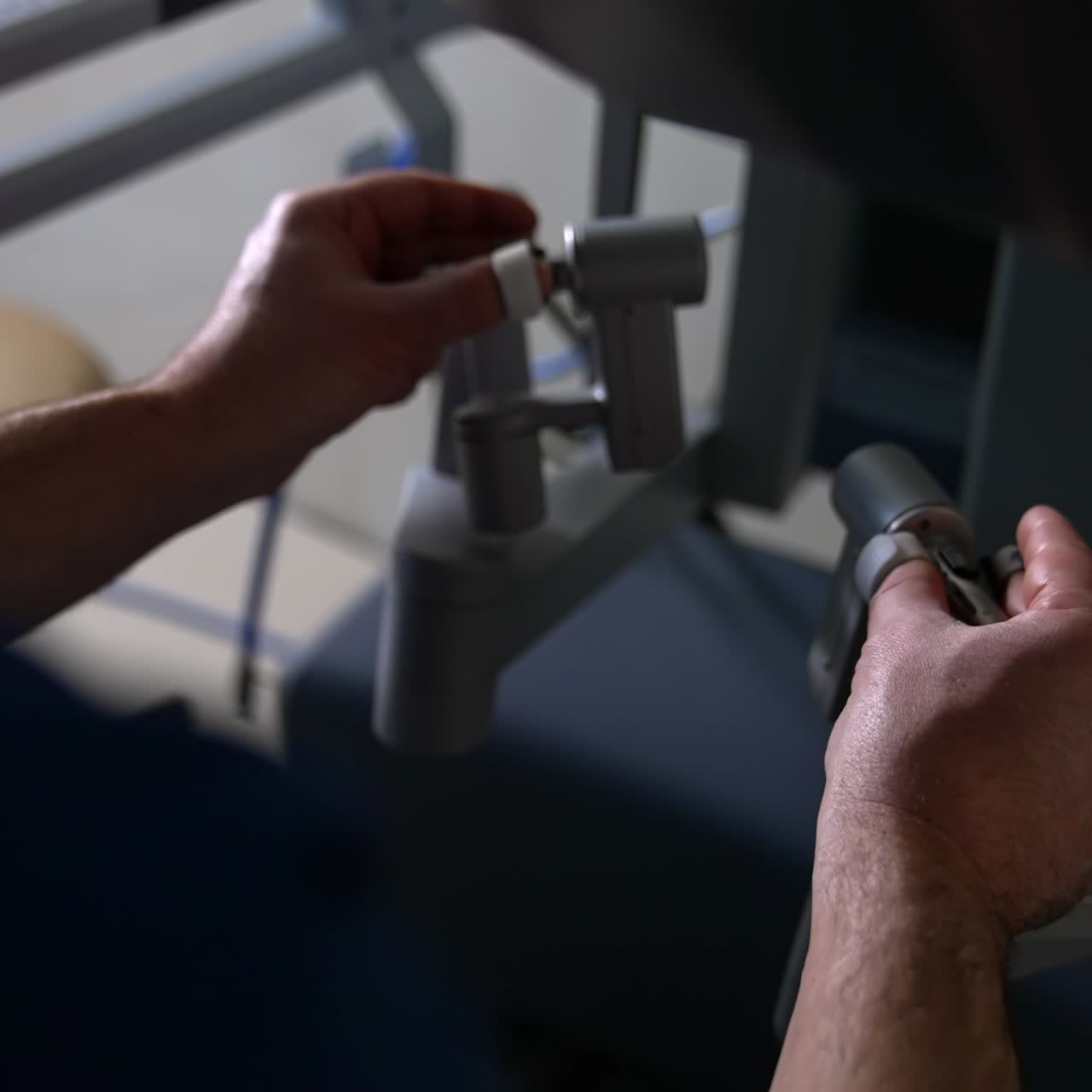 Looking close at the hands of healthcare professional operating Da Vinci robot. Doctor carefully moves his hands to move robotic arms