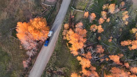 Vista-Superior-Que-Muestra-Una-Hermosa-Carretera-Secundaria-Y-Colores-Otoñales-Mientras-Un-Jeep-Azul-Y-Una-Corriente-De-Aire-Recorren-Esta-Aventura