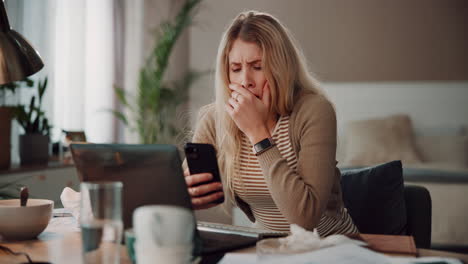 tired woman working at home office, yawning and looking at her phone