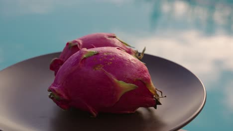 dragon fruit on a plate with swimming pool in the background at sunset