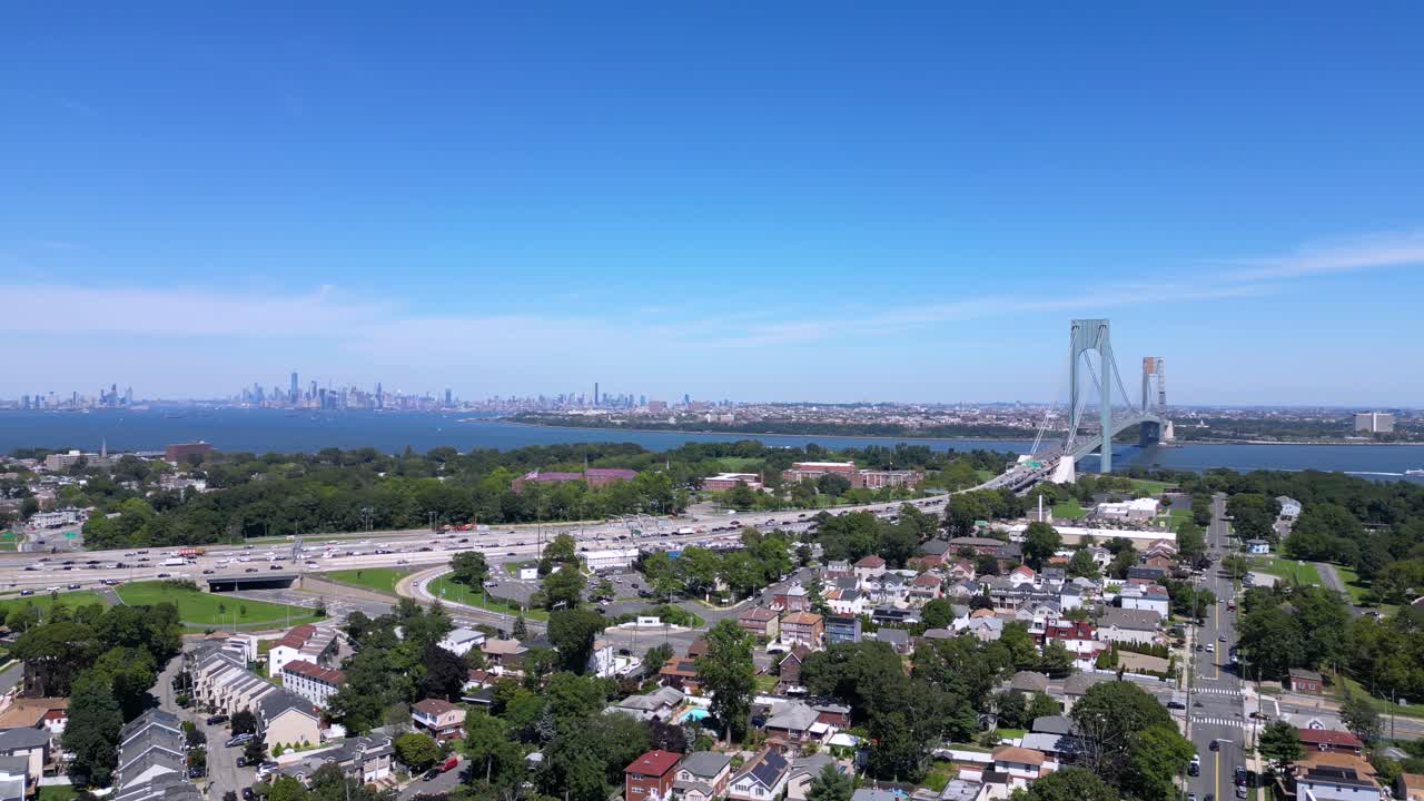 Stunning aerial view of Staten Island and the Verrazzano-Narrows Bridge with a clear skyline, waterfront, and residential neighborhoods under a bright blue sky