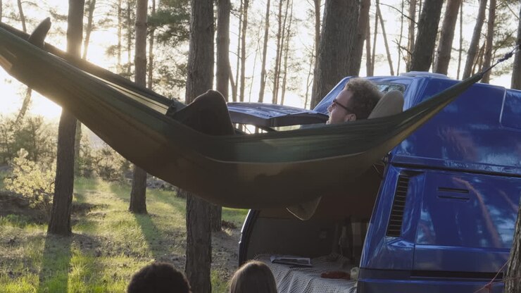 A Multiethnic Group Of Friends Lying In Hammocks In The Forest
