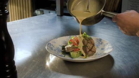 chef pours sauce on the foodplate