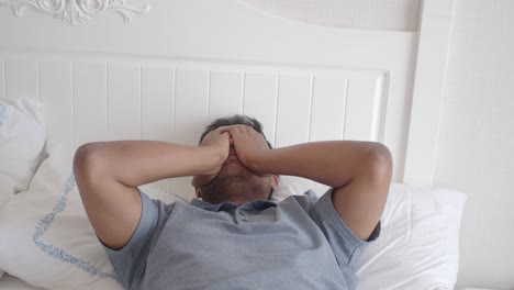 man covering his face in bed