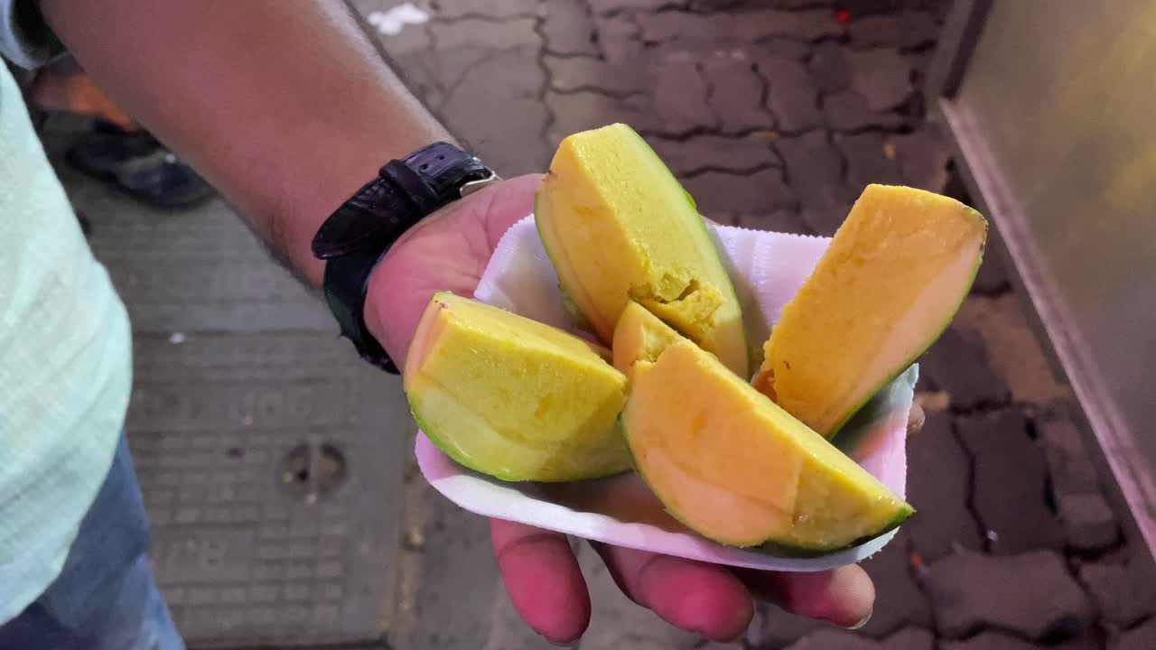 video de un hombre comiendo el delicioso y cremoso kulfi de mango, una golosina india congelada que es similar al helado de mango pero preparado con mango