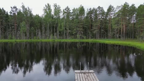 Peace-and-solitude-at-small-boreal-lake,-aerial-flight-over-small-dock