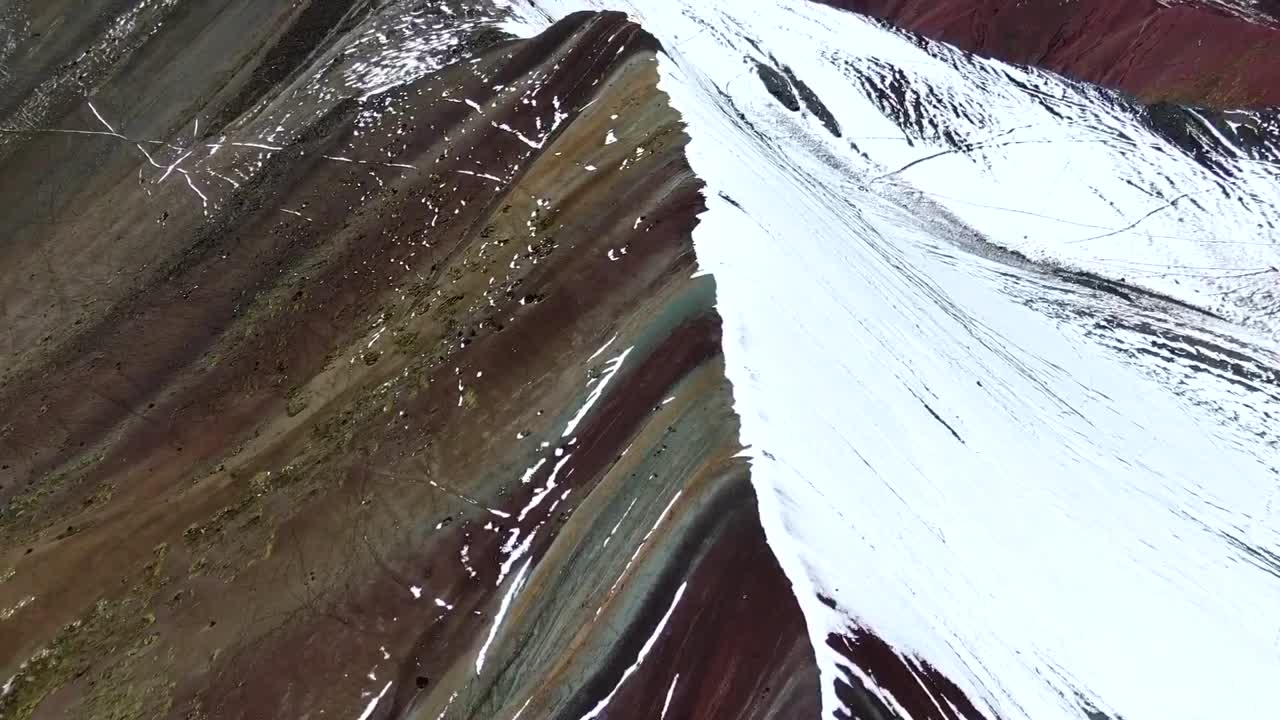 큐스코의 레인보우 산 위를 날아다니는 페루의 드론 뷰, 절반이 눈으로 여있는 산과 다른 다른 은 색을 보여줍니다.