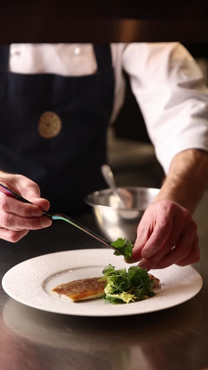 Chef che impiattano un piatto con pesce e insalata