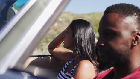 African-american-couple-driving-along-country-road-in-convertible-car
