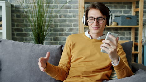 young man enjoying music on smartphone at home
