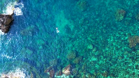 male tourist swimming in the transparent waters of a bay in ibiza, spain. tremendous aerial view flight drone top down above view