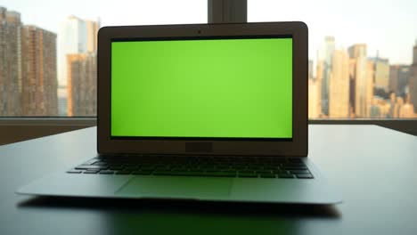 business laptop with green screen chroma key monitor and cityscape background.