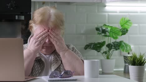 tired senior woman finished using computer laptop at home office