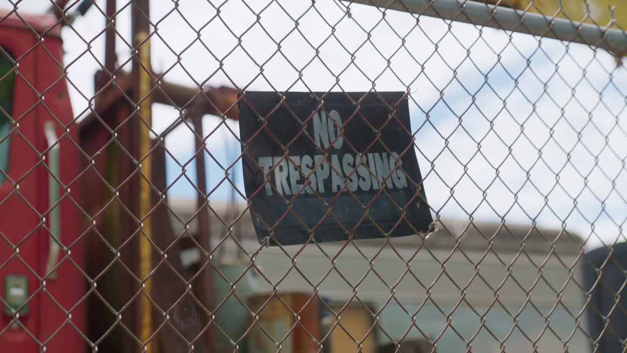 No trespassing sign attached to metal fence in closed and gated private property. Rustic and locked gate with warning sign prohibiting access and entry to house or business area. Privacy laws