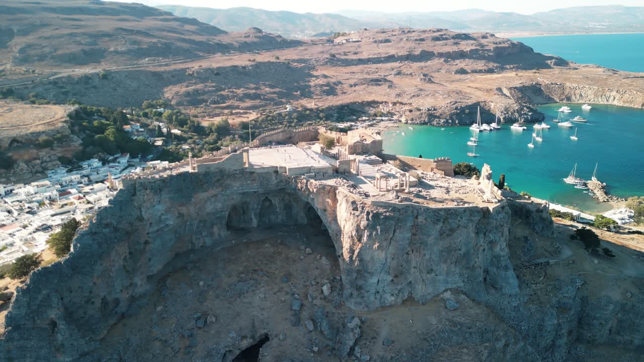 Stunning Lindos Acropolis aerial drone rotate from far, revealing coast, Rhodes, Greece