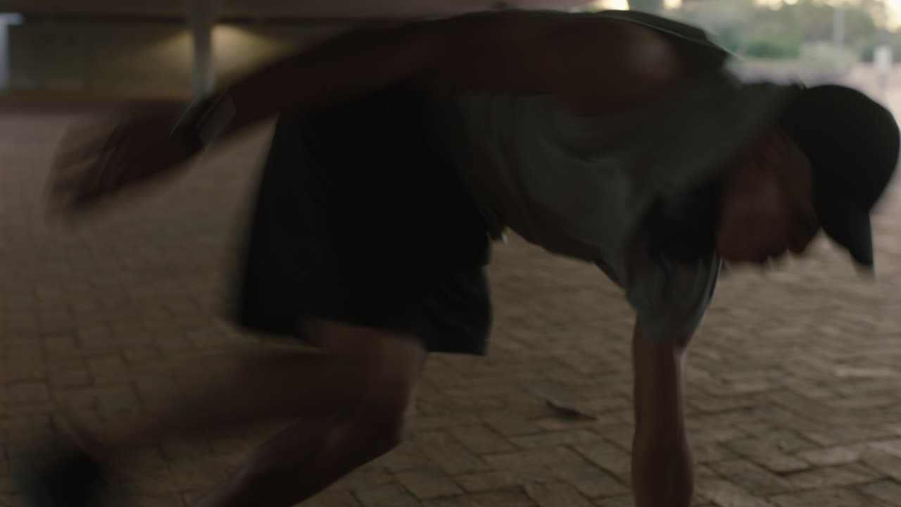 hombre bailando joven breakdancer de raza mixta realizando movimientos de baile moderno de hip hop practicando coreografía de estilo libre urbano en la ciudad al atardecer de cerca