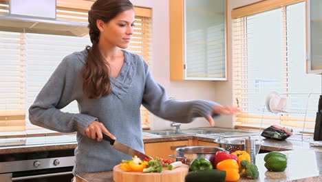 una mujer morena cortando pimientos.