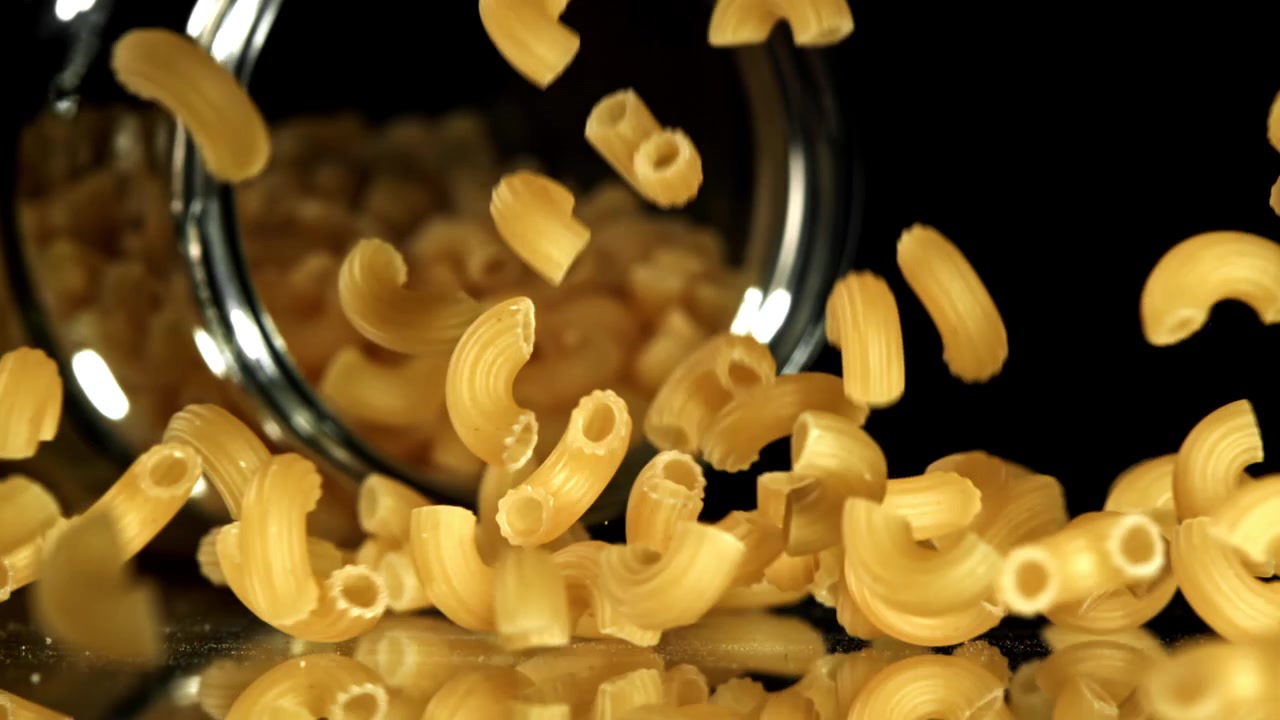 Maccheroni secchi che cadono da un barattolo di vetro al rallentatore