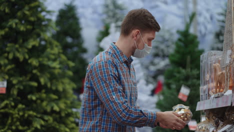 shopping in pandemic and quarantine. a man in a protective mask in a jewelry store and garlands with toys for christmas trees and at home. christmas garlands and decor.