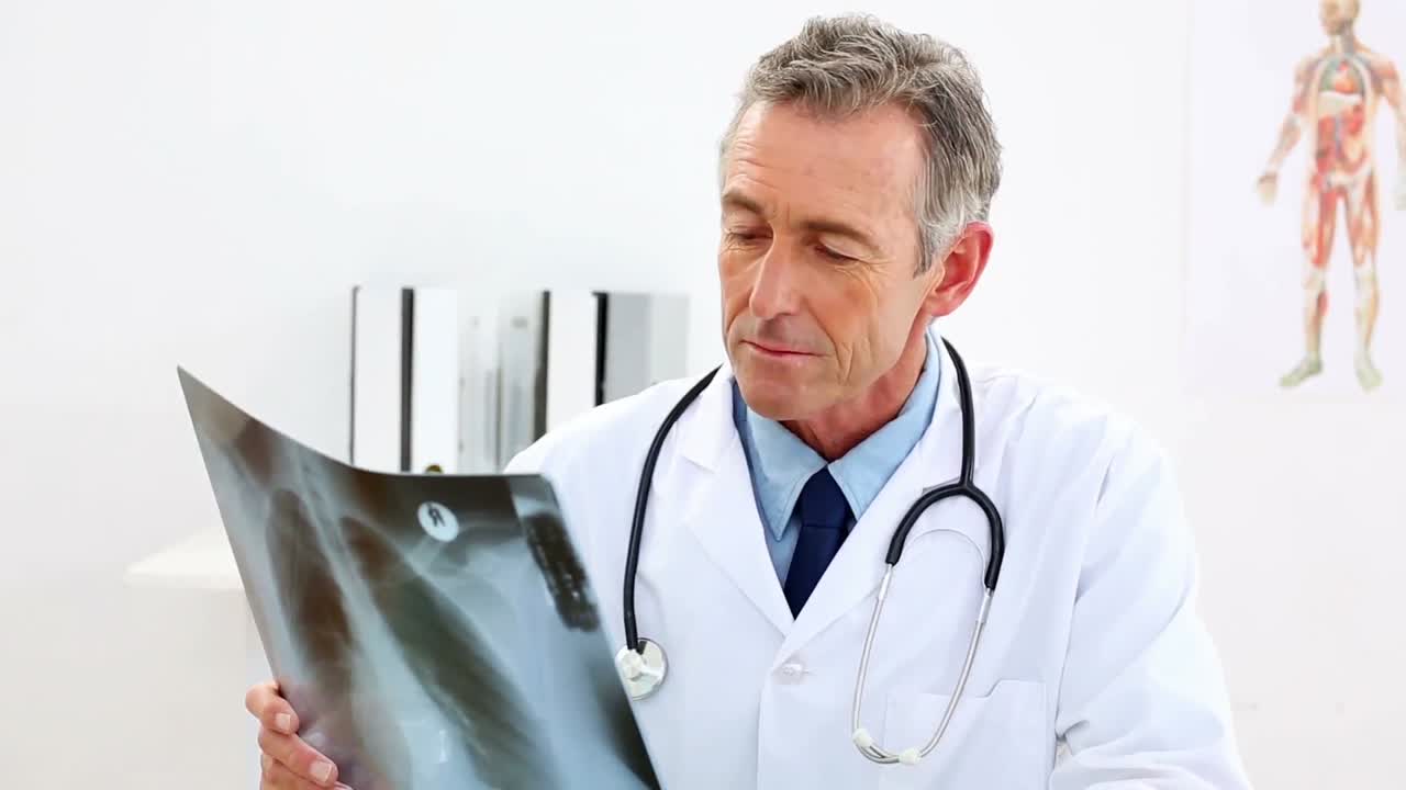 Mature doctor looking at xray at his desk