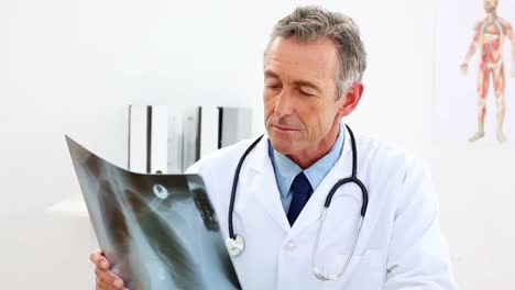 médico maduro mirando rayos x en su escritorio