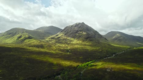 clouds cast shadows on lush green scottish marshland and mountains, isle of skye