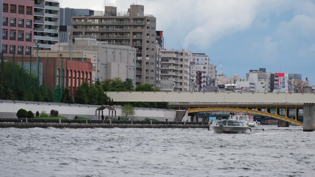 Experience a tranquil boat on Tokyo's Sumida River amid towering urban structures. Soft lighting and dynamic movement enhance this captivating cityscape footage